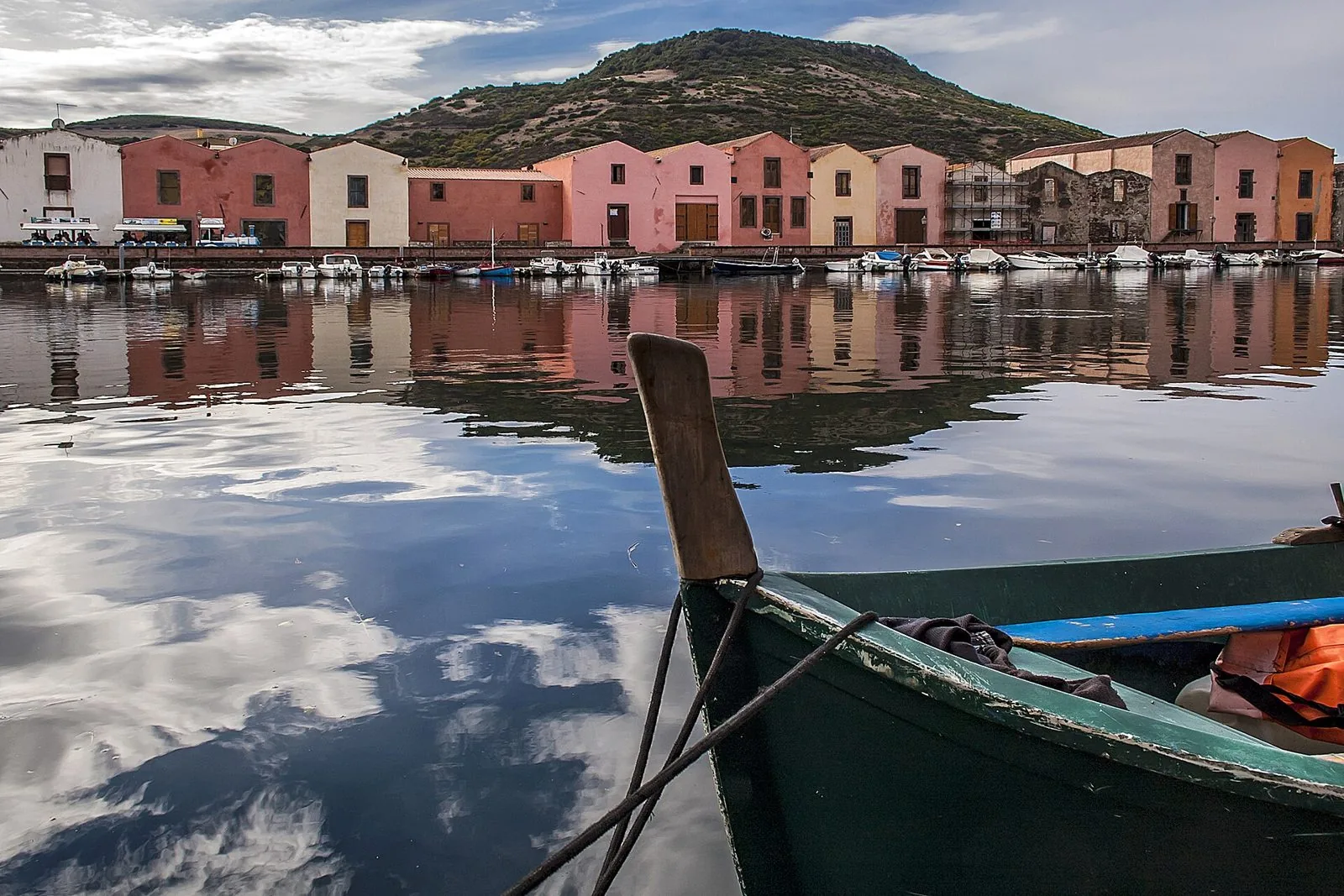 Le facciate colorate delle antiche concerie di Sas Conzas riflesse nel fiume Temo, con una barca in primo piano